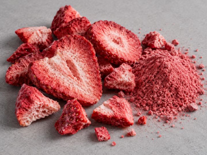 Trozos y rodajas de fresa liofilizada junto a polvo de fresa.